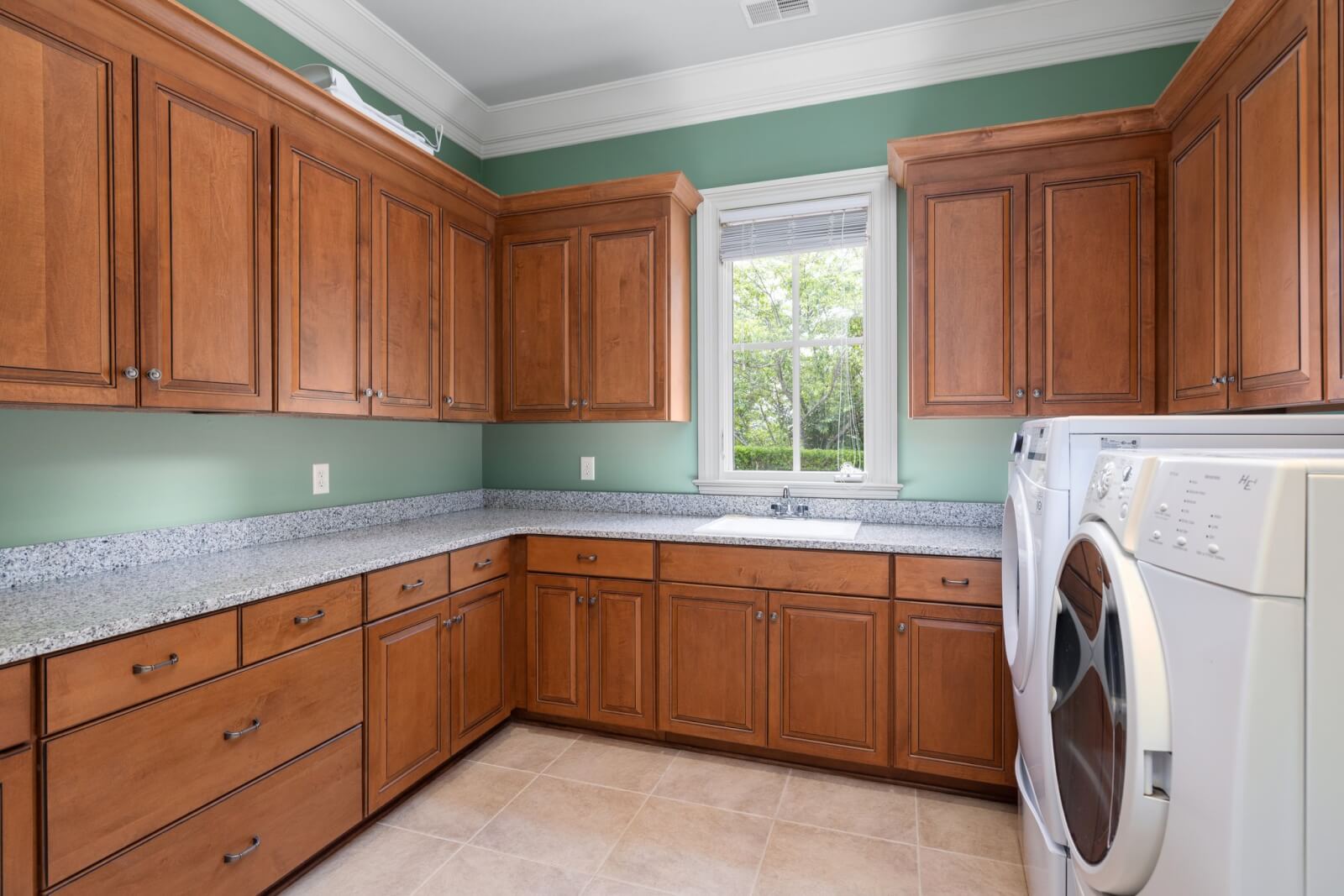 Laundry room with dark cabinets and green walls