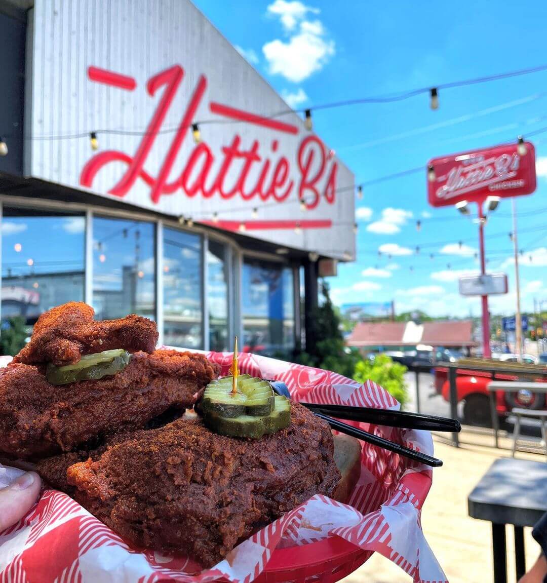 A basket of hot chicken in front of the Hattie Bs sign