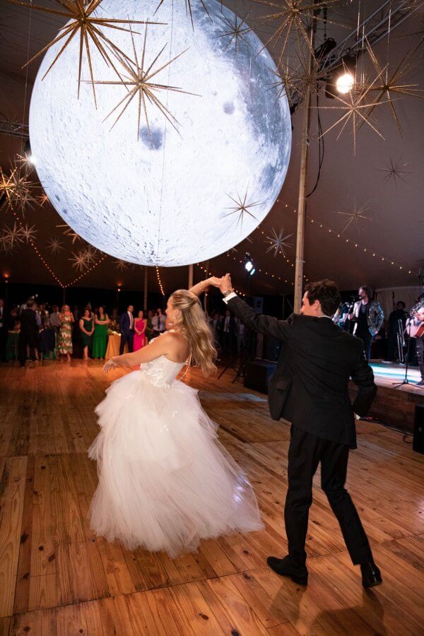 A Wild Storybook Wedding You Won't Believe - 21 Bride and groom dance underneath a huge moon prop on a dancefloor