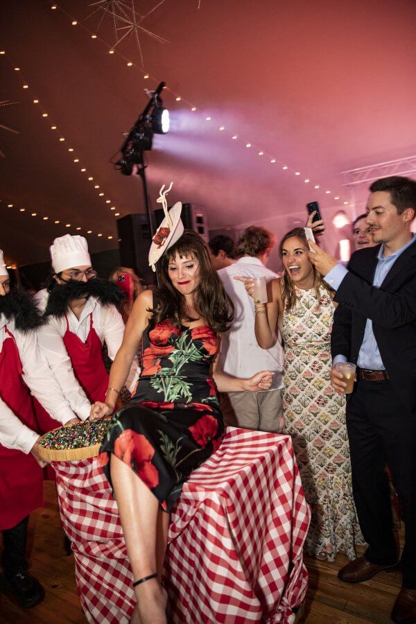 A Wild Storybook Wedding You Won't Believe - 24 Woman in brunette wig on a checked tablecloth being pushed by Italian costumed serves
