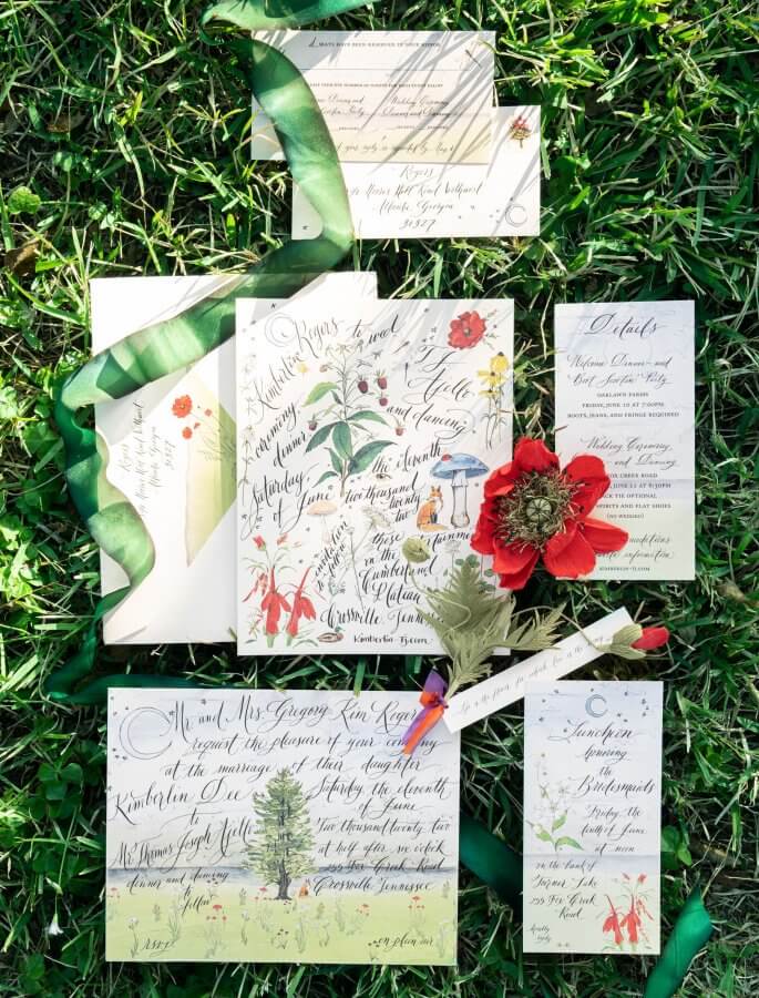 A Wild Storybook Wedding You Won't Believe - 3 Stationary wedding suite flat lay on green grass