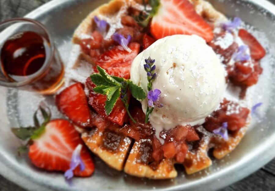 Brunch plate of waffles, berries, and whipped cream at Belles Bistro 