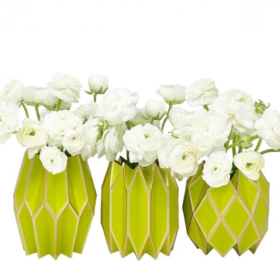 Three lime green geometric vases, each hold white ranunculus flowers against a plain white background.