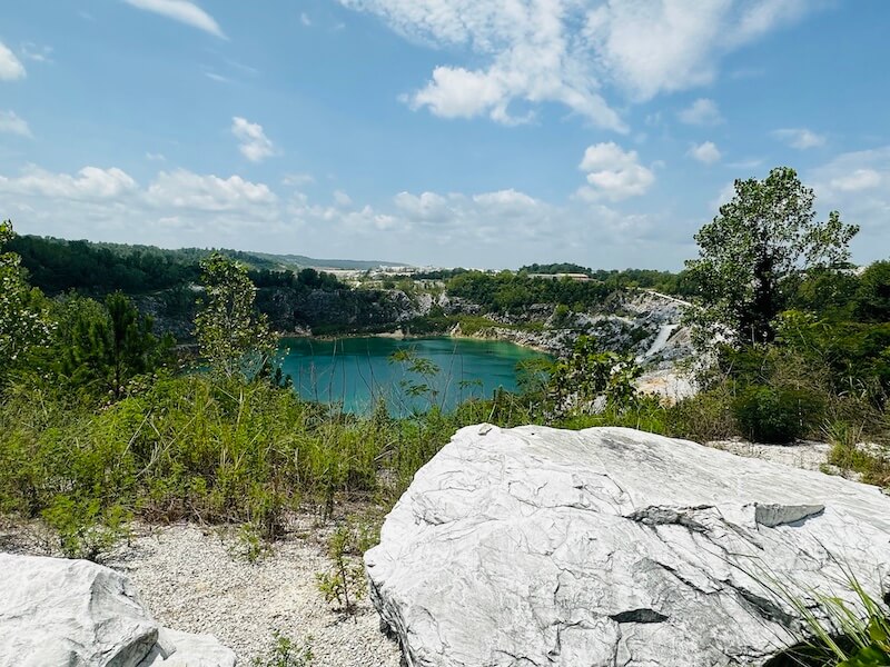 Large marble rock in the forefront and an overlook of a marble quarry