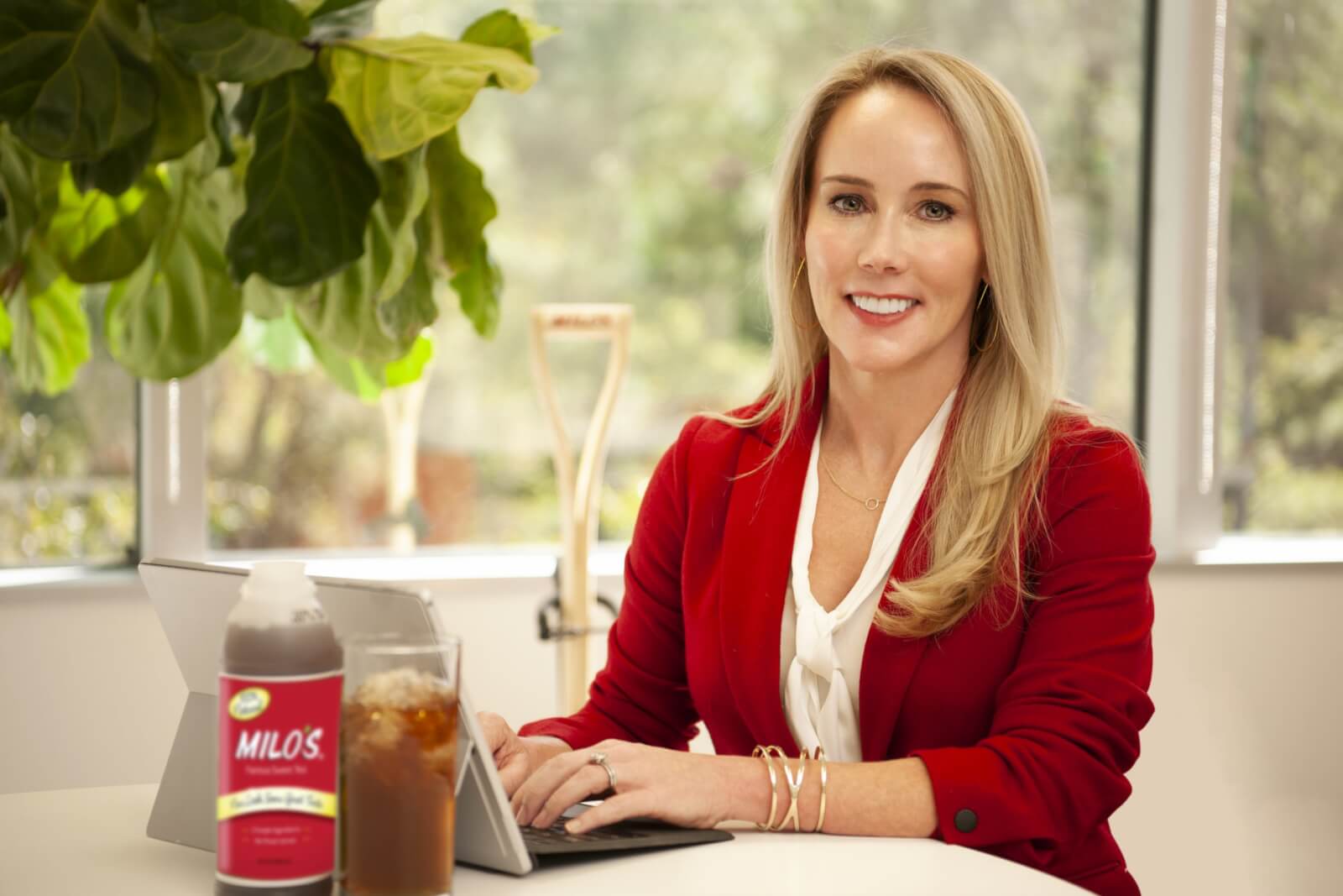 Blonde woman in a red blazer typing on a computer.