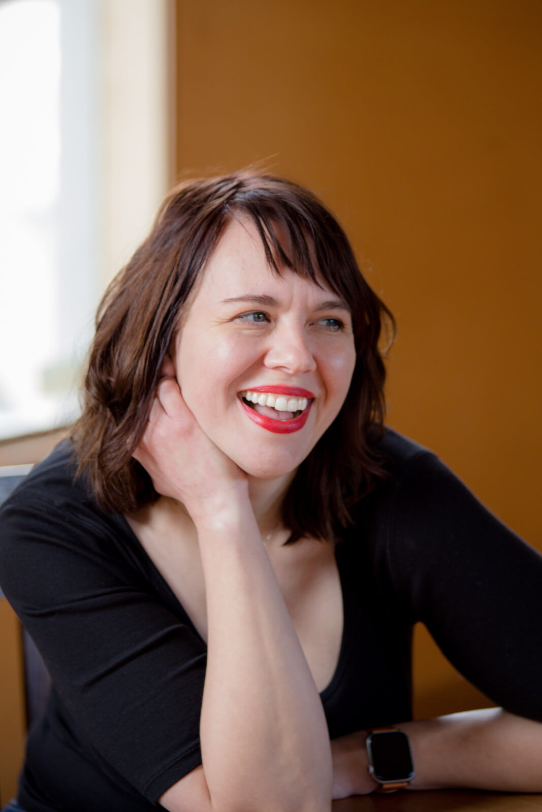 Brunette woman in red lipstick smiling into the distance.