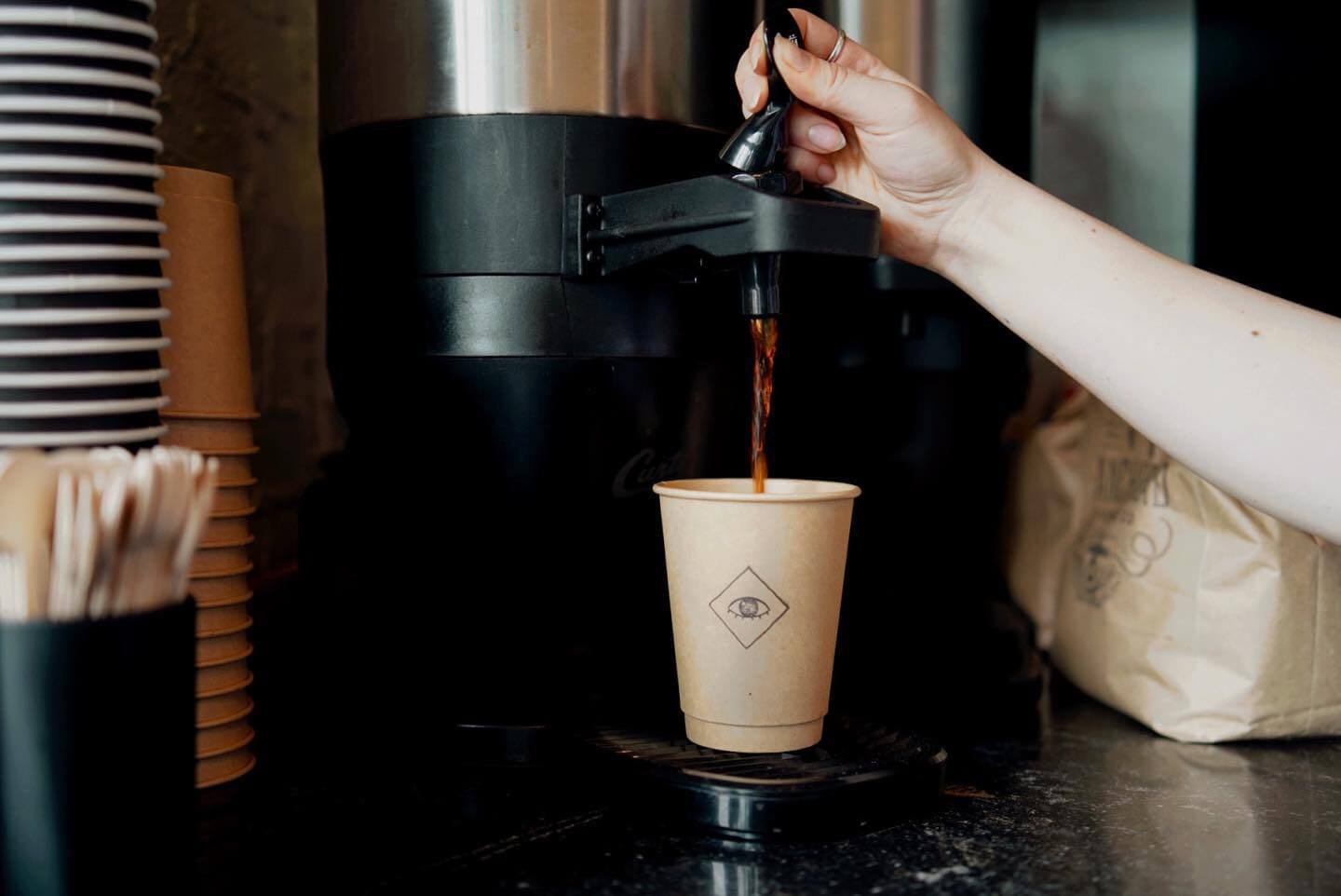 Hand filling an Elegy coffee cup