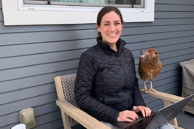 Woman in black jacket with laptop and a chicken