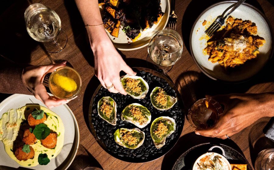 People's hands and dishes on a dinner table at Sojourner at Southall Farm 