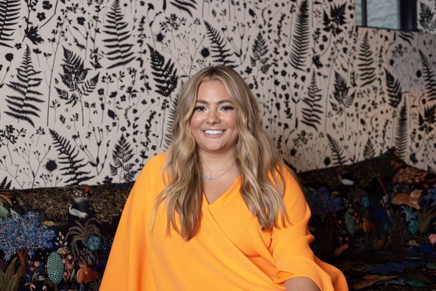 Sarah Collins Lawler sits for portrait in bright orange kaftan from Tela Luxury Mercantile