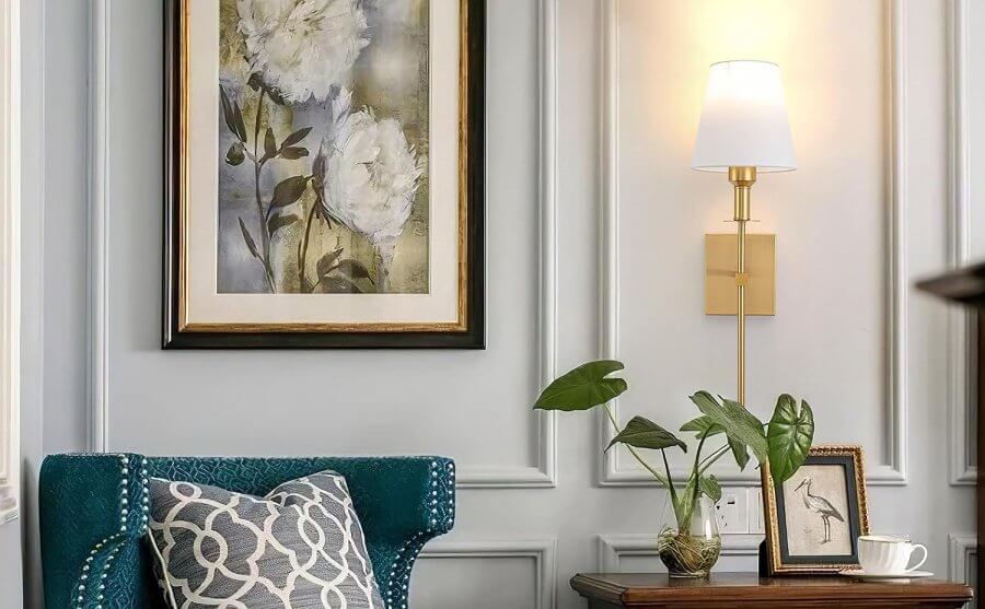 Pretty white and brass wall sconce next to hanging painting 