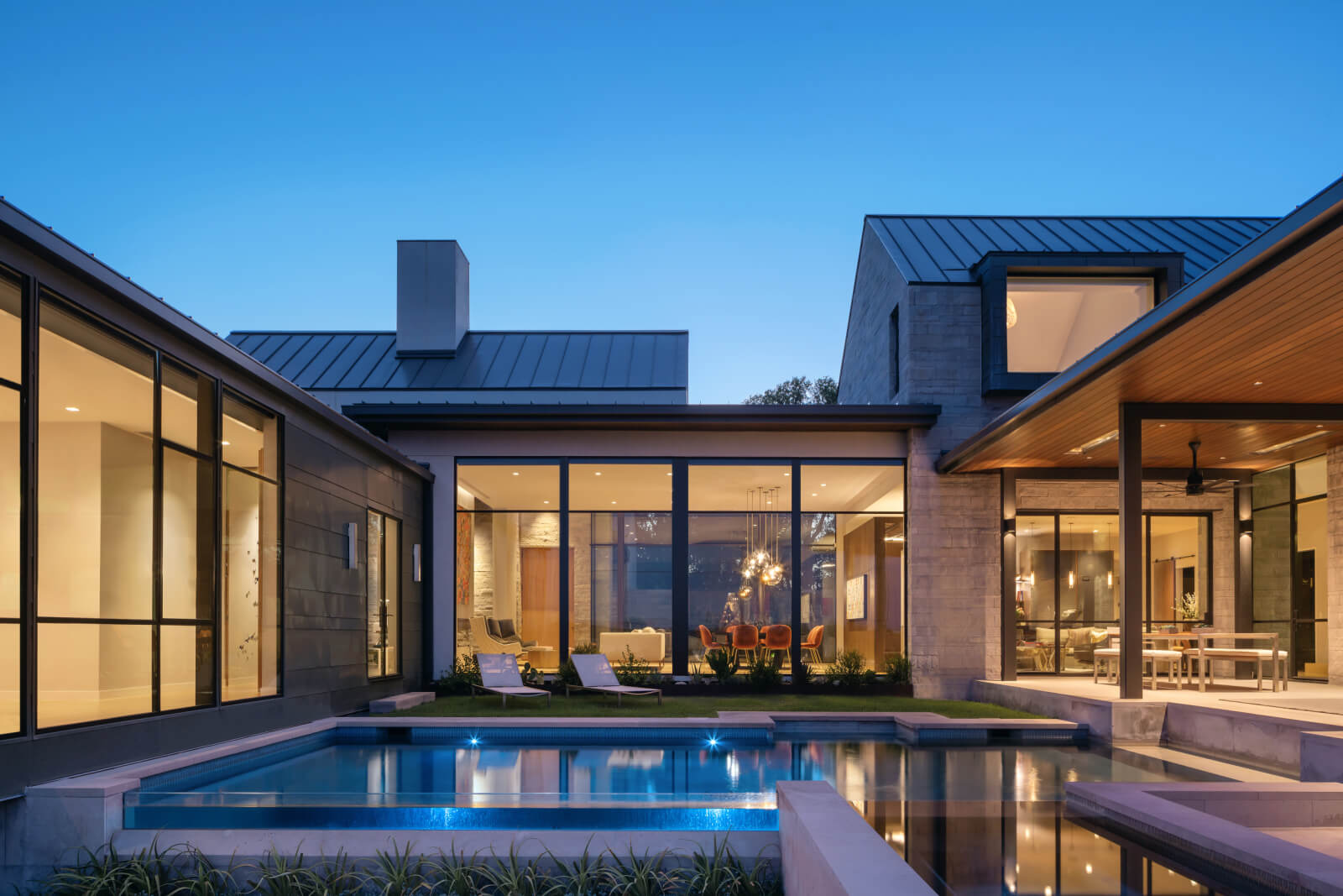Exterior view of pool surrounded by house at dusk