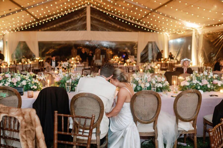Bride and groom holding hands at a reception table