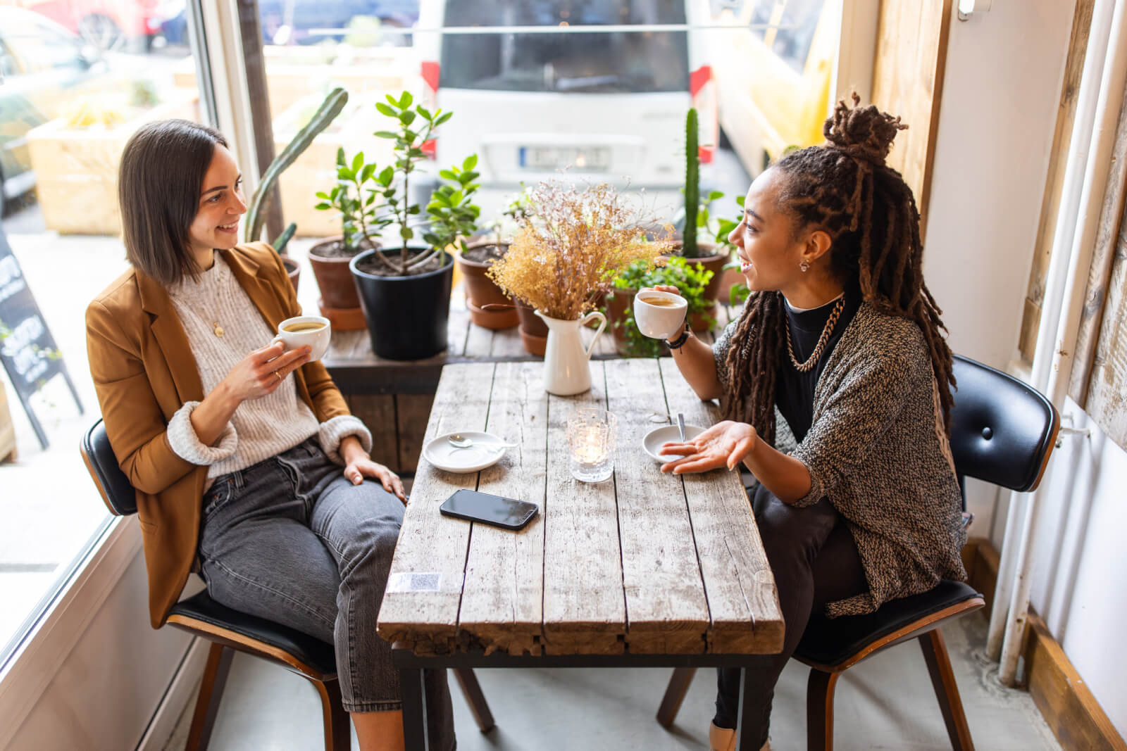Businesswomen talking while having coffee at a coffee shop.