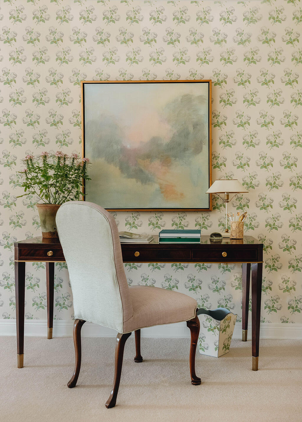 Dark wood desk in front of floral wallpaper with abstract art