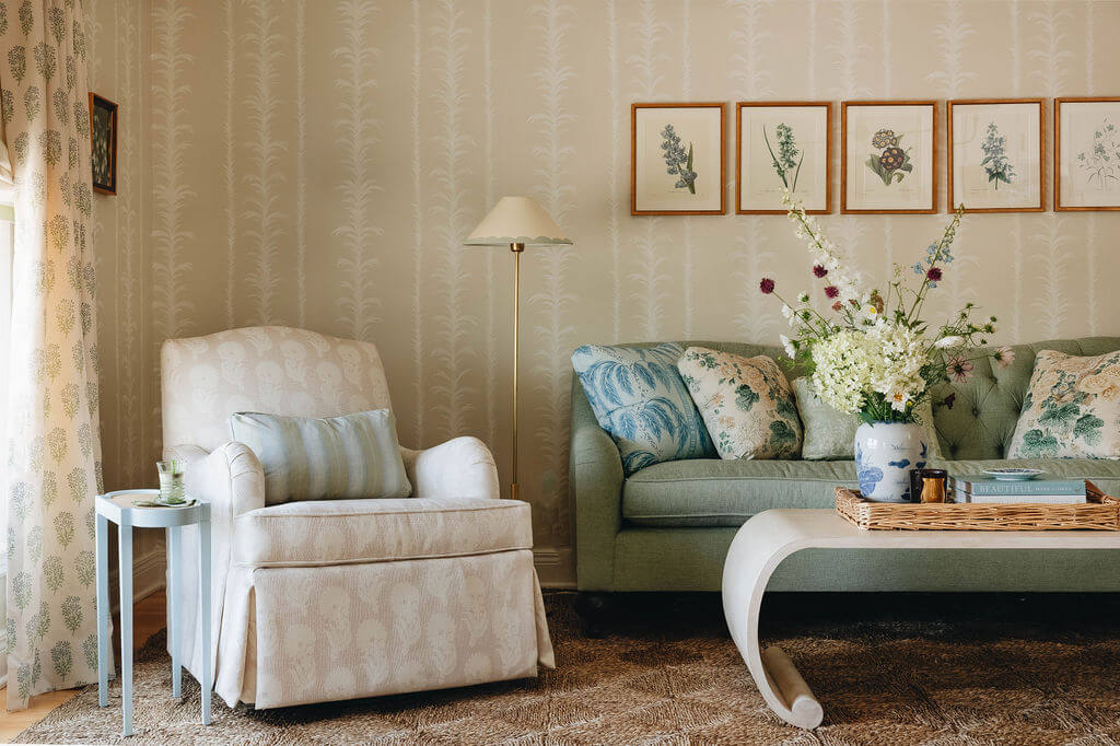 Living room with flower prints on floral wallpaper, green couch, modern coffee table, and comfy recliner