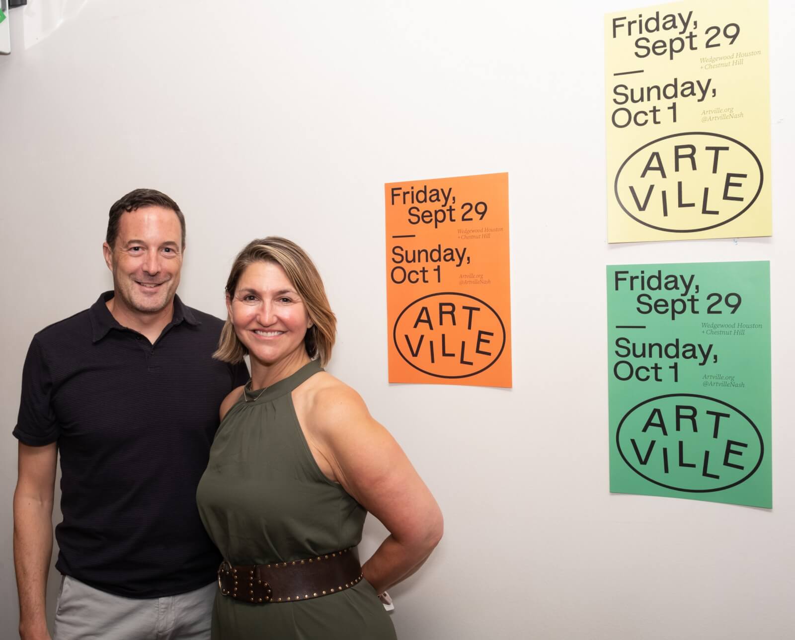 Man and woman posing in front of Artville posters