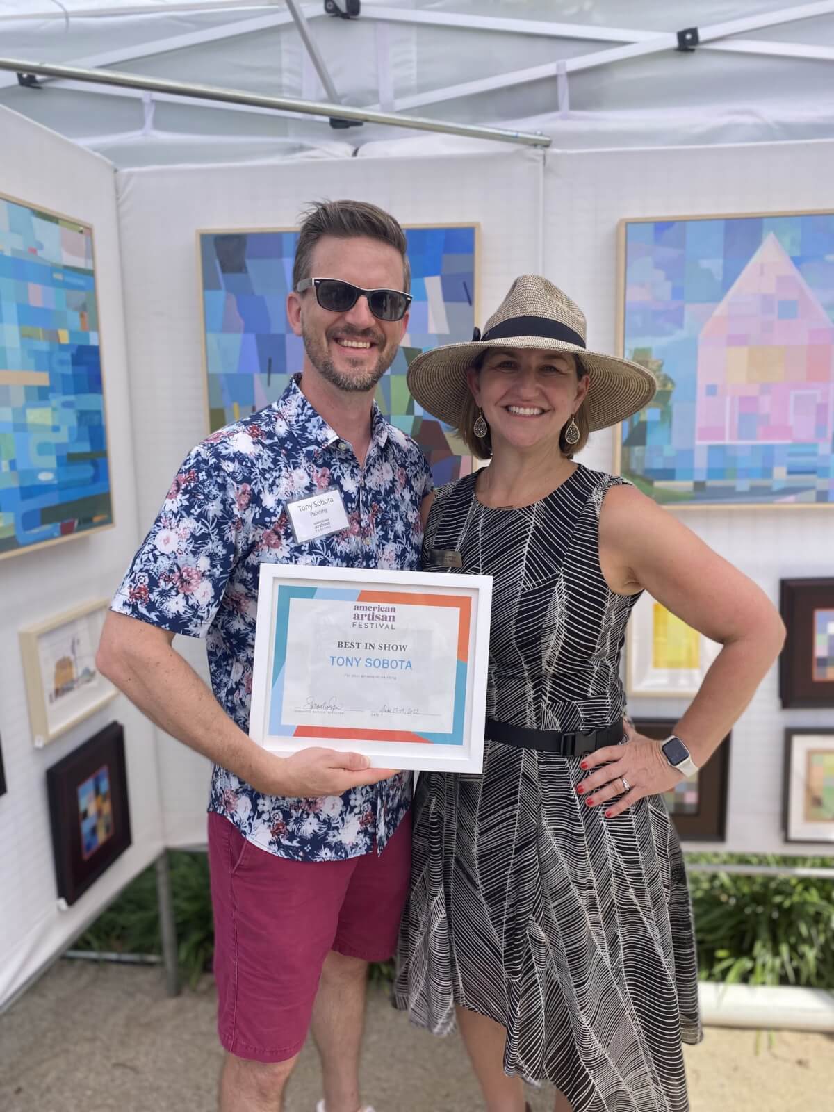 Woman in hat posing with man holding certificate