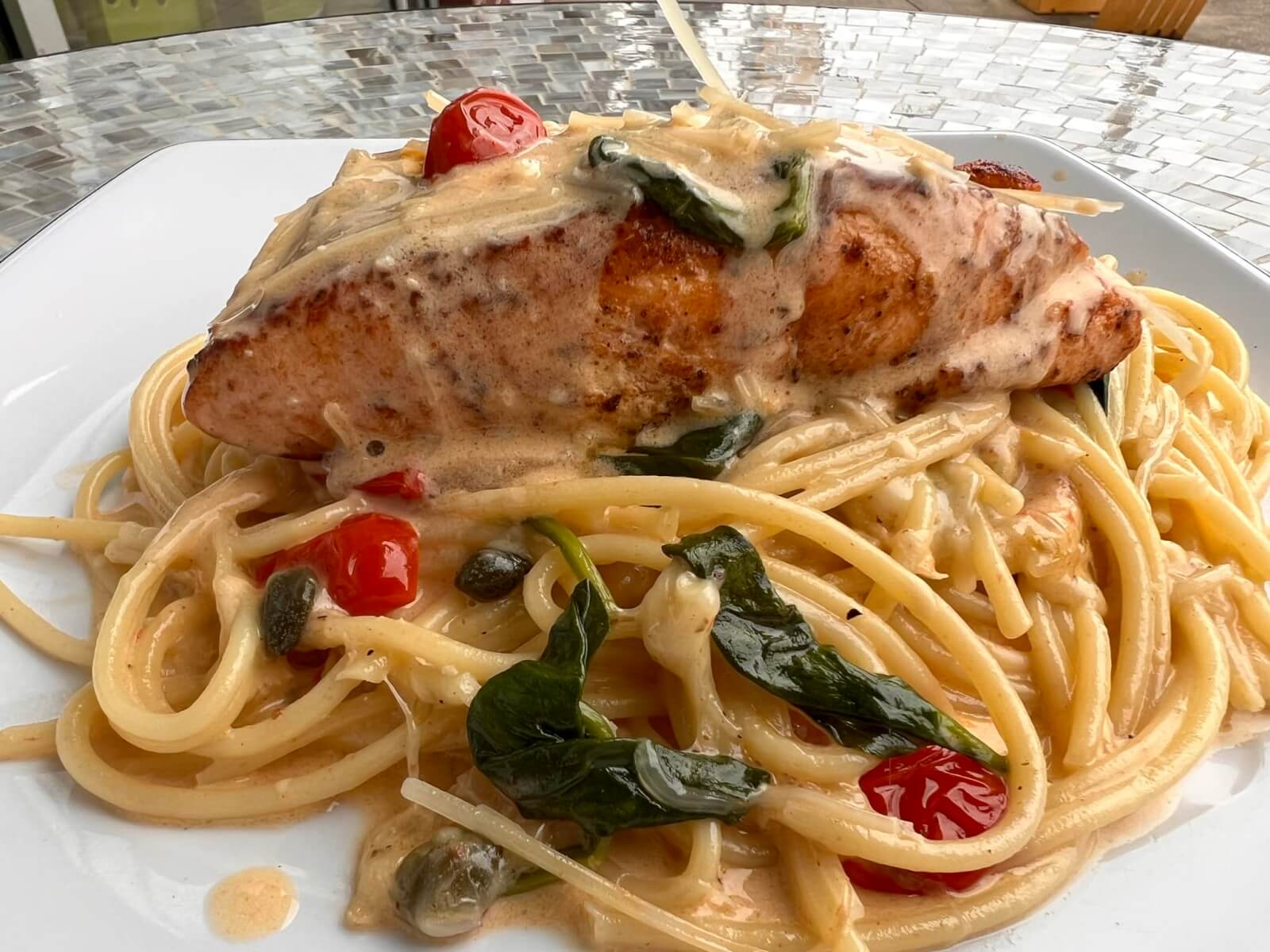 Salmon on top of a bed of pasta.