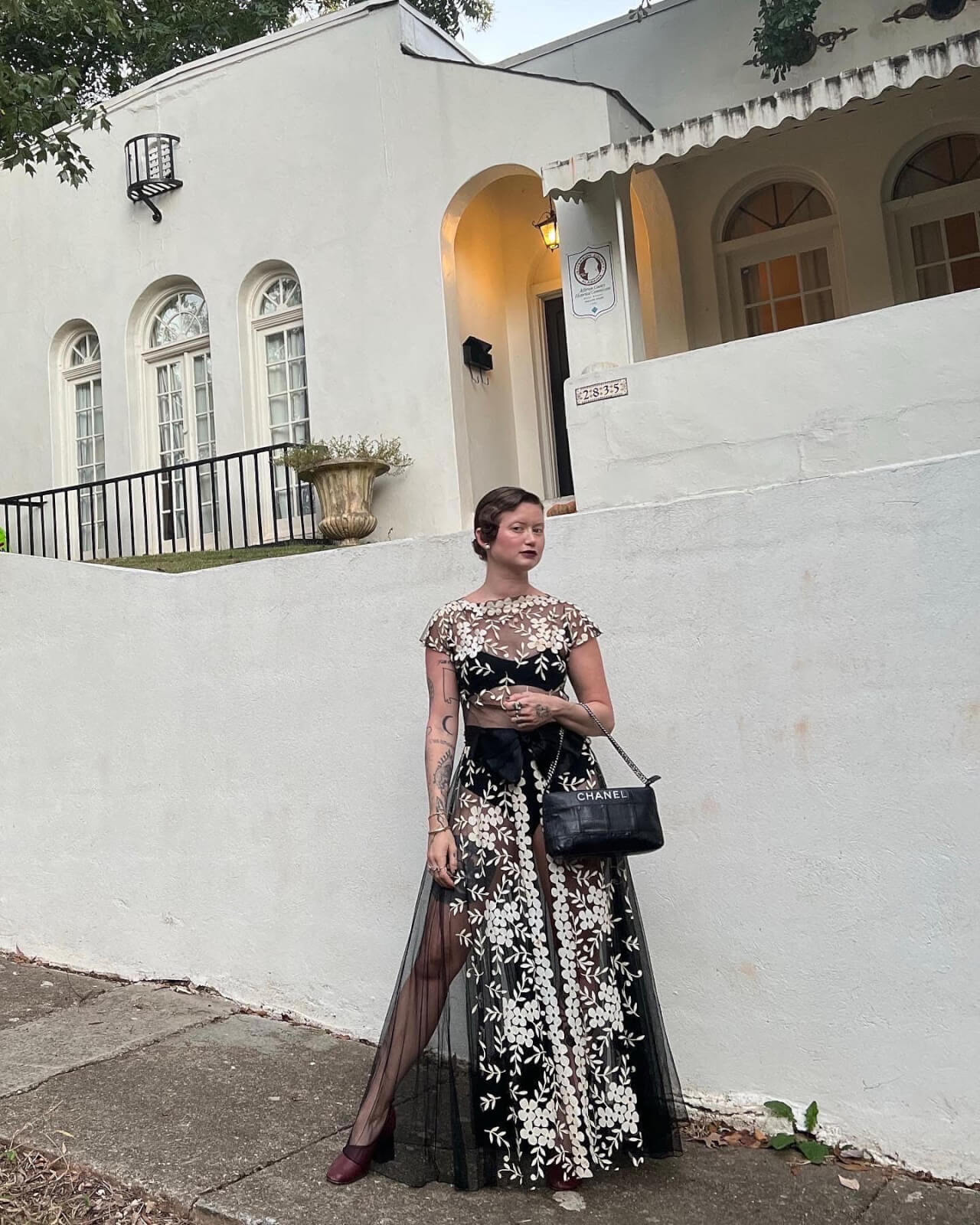 Devore Vintage owner Hannah Conzelman poses in a vintage gown with a Chanel handbag outside her historic Spanish revival home.