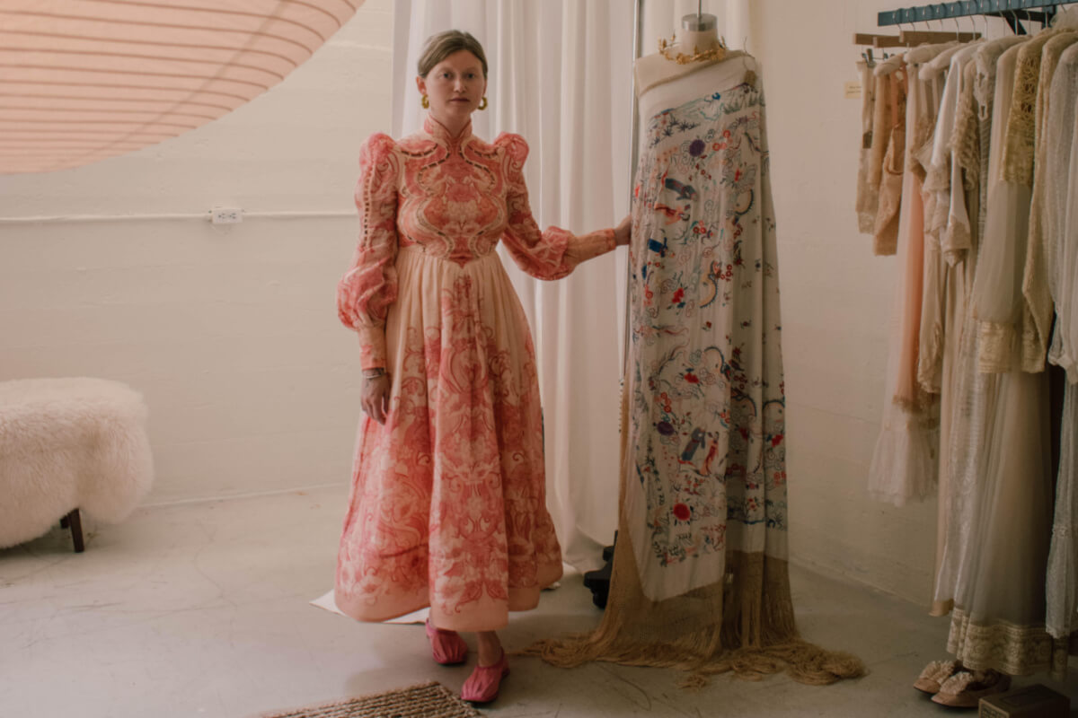 Woman in prairie dress posing next to vintage mannequin
