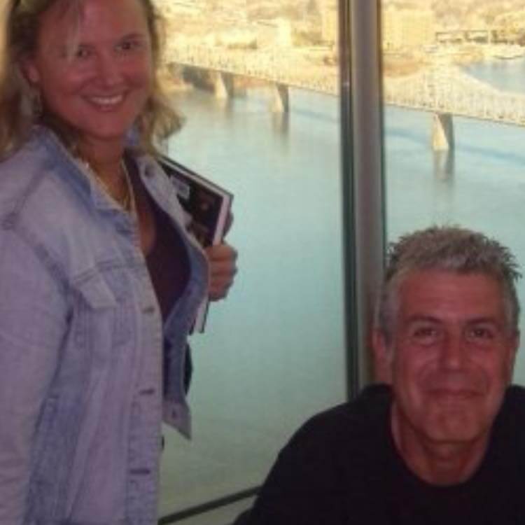 woman smiling next to Anthony Bourdain