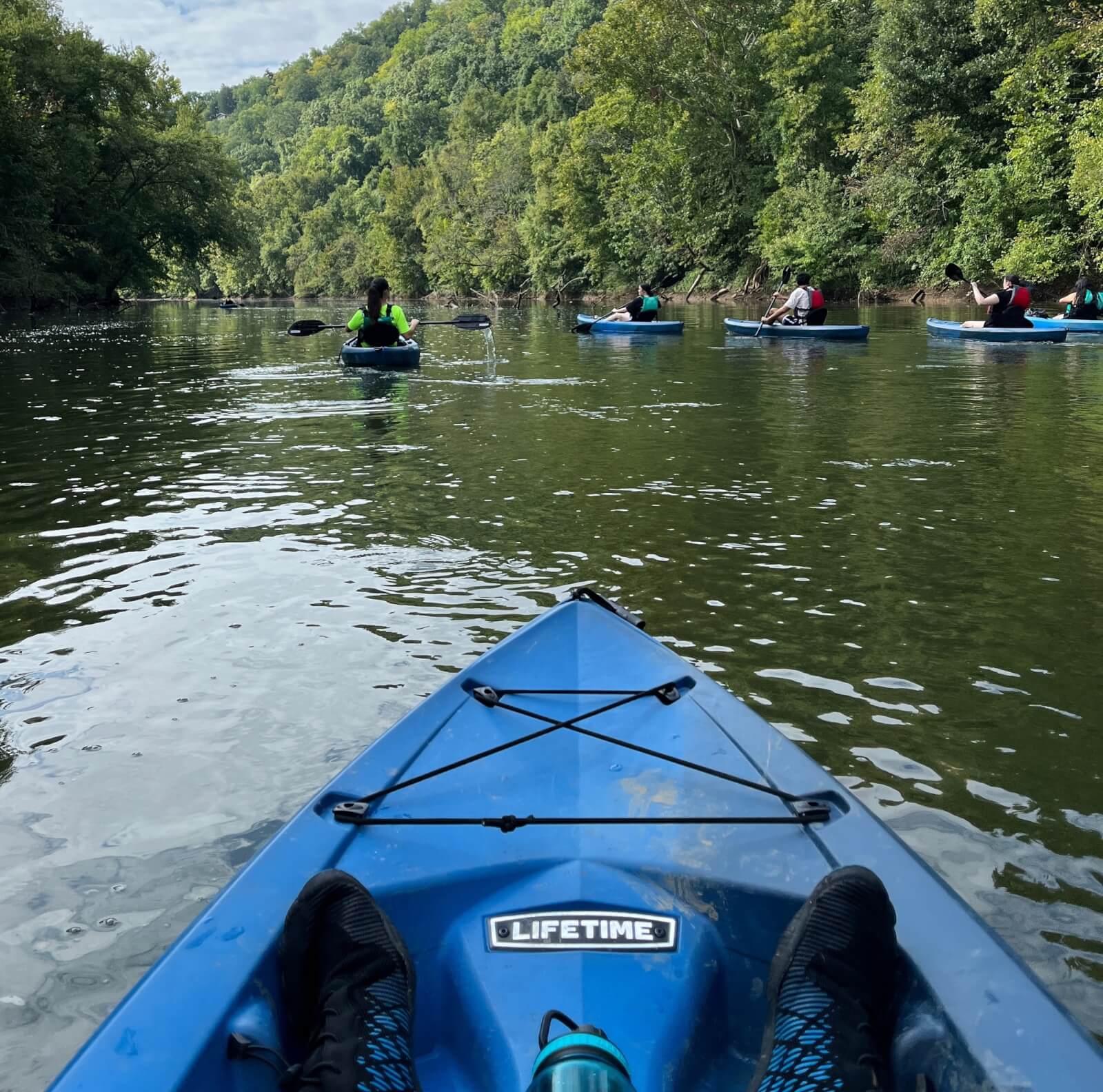 Person kayaking with others on river