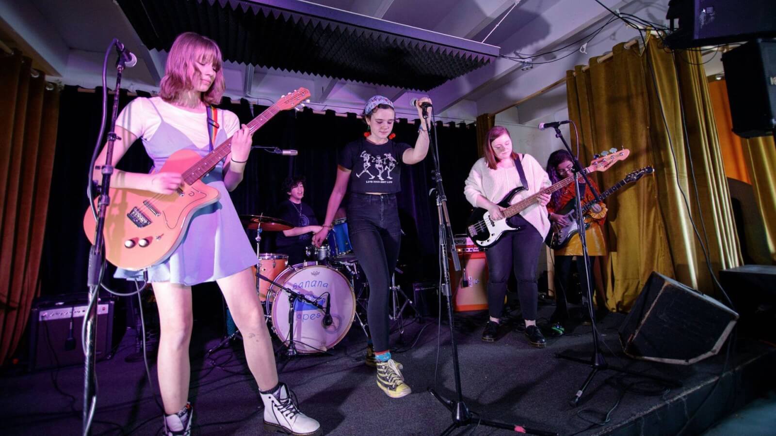 Young female rock band performing on stage.