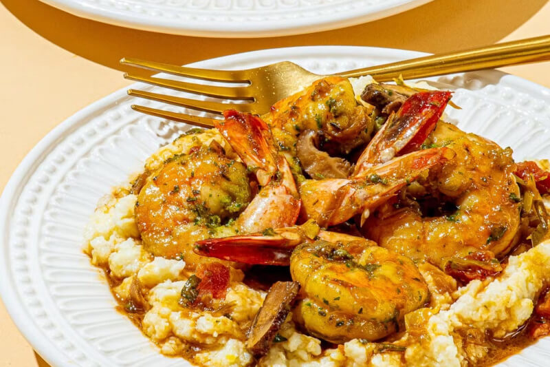 shrimp and grits on a white plate with a fork