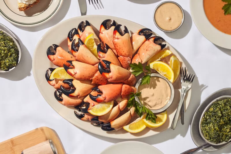 crab claws on a platter with sauce and lemon slices 