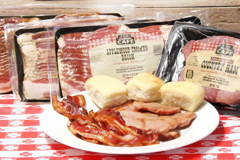 bacon, ham and biscuits on a plate that is sitting on a red checkered tablecloth 