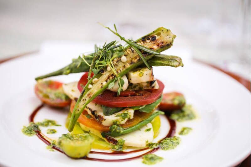 tomatoes and okra stacked on a white plate