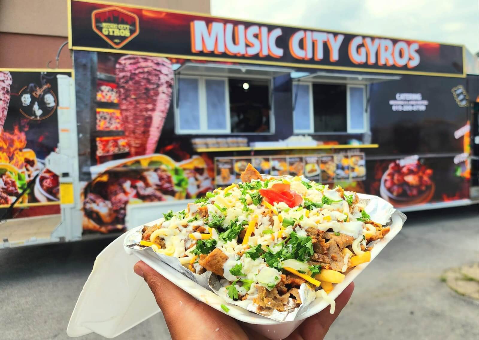 Person holding gyro in front of a food truck