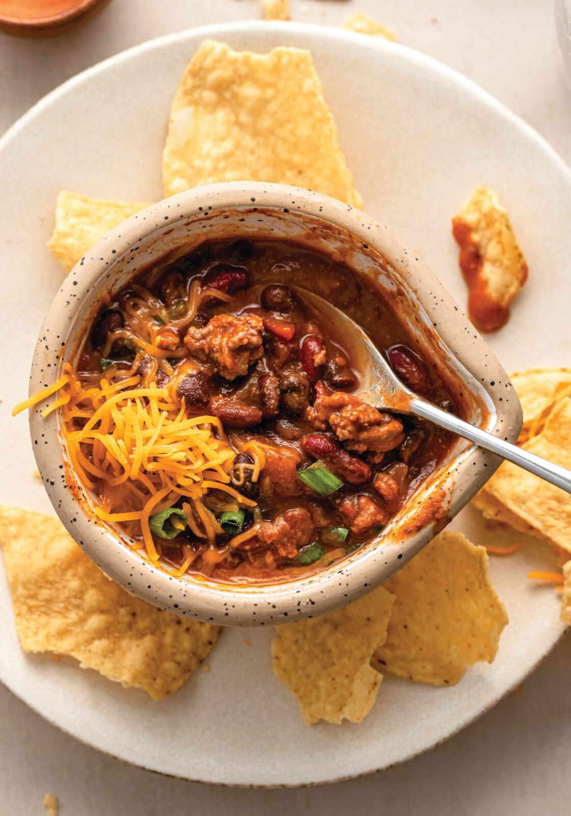 bowl of chili on a plate with tortilla chips