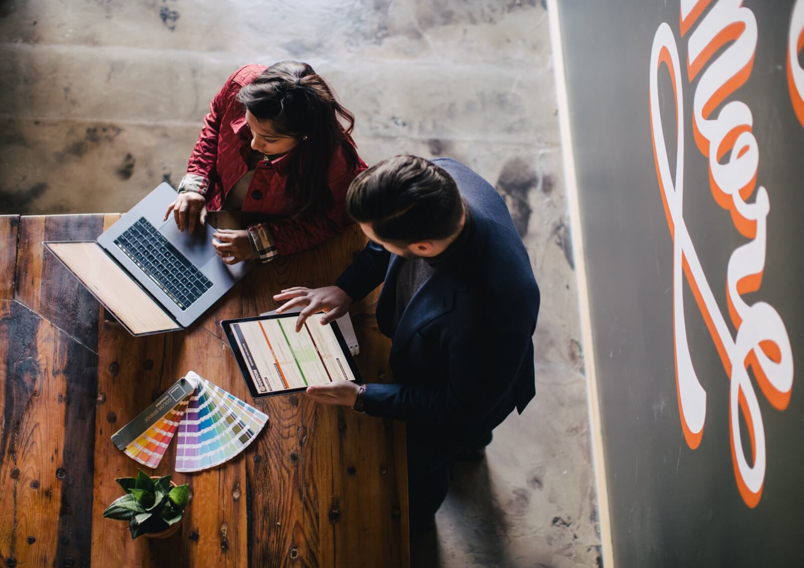helicopter view of two people working on their laptops in an office