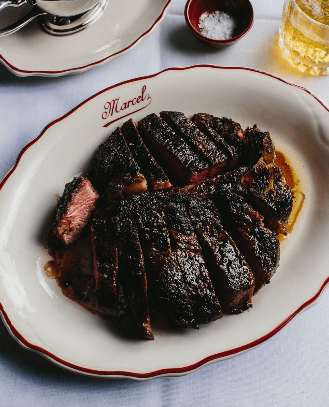 steak on a white plate that says Marcel in red
