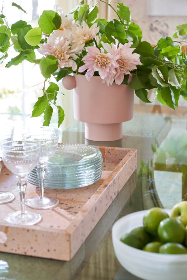 Pink art deco tray near a pink vase of flowers and a bowl of limes