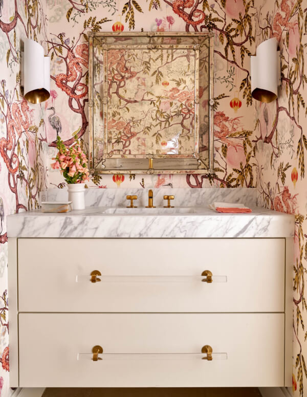 Bathroom with ornate pink wallpaper over marble-topped sink