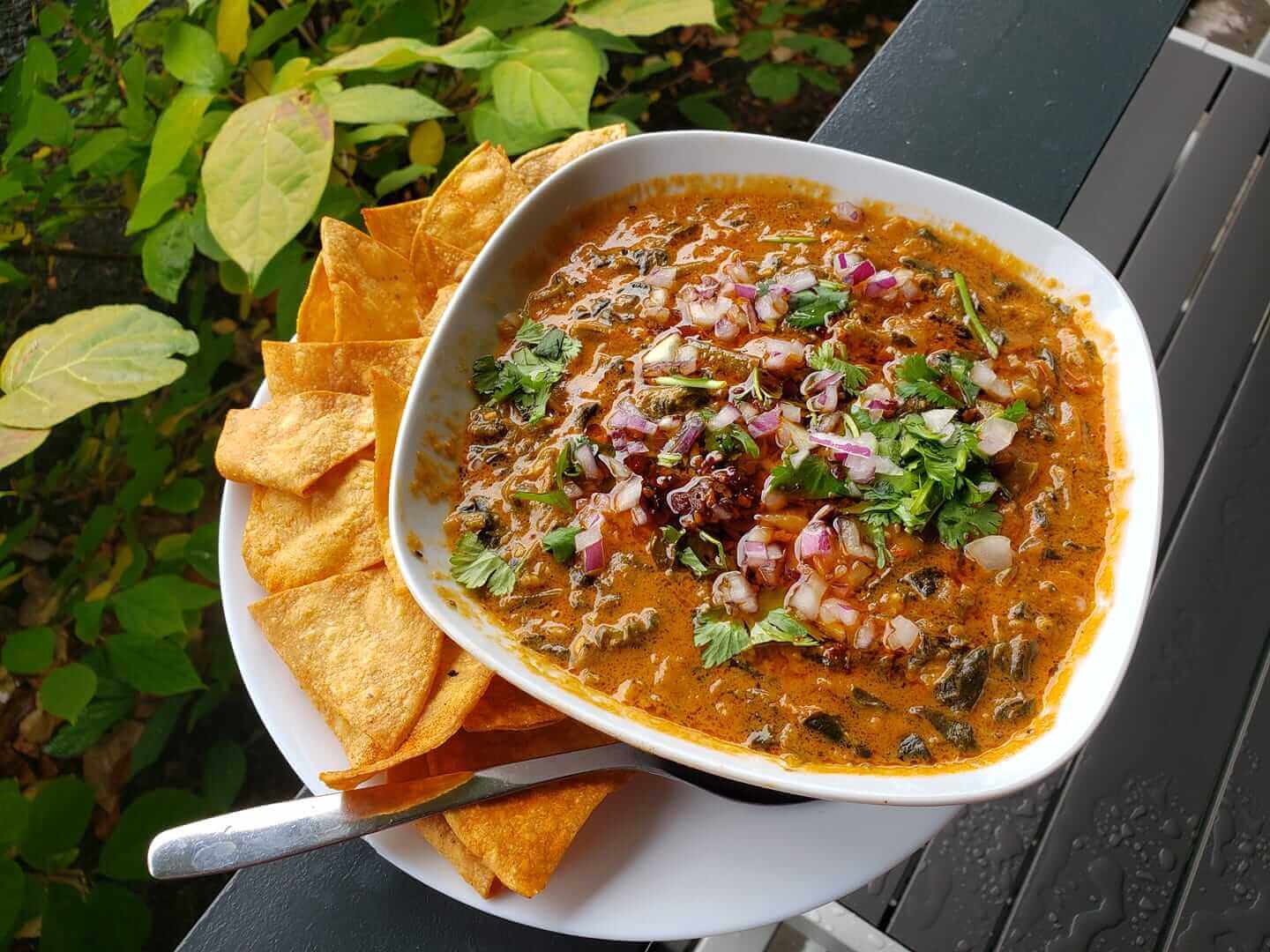 spinach and peanut soup on plate with chips
