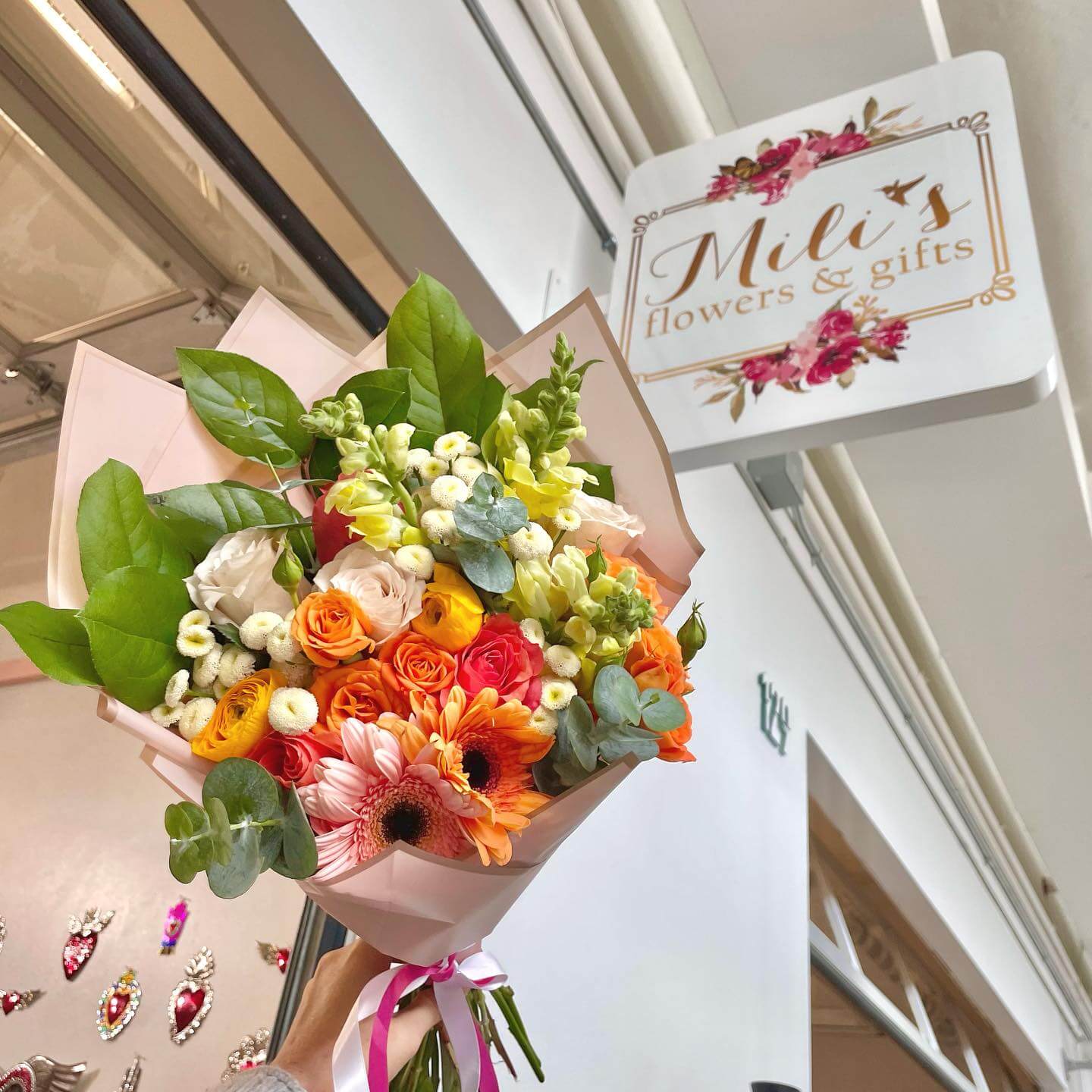 floral bouquet held up in front of Mili's flowers and gifts boutique sign