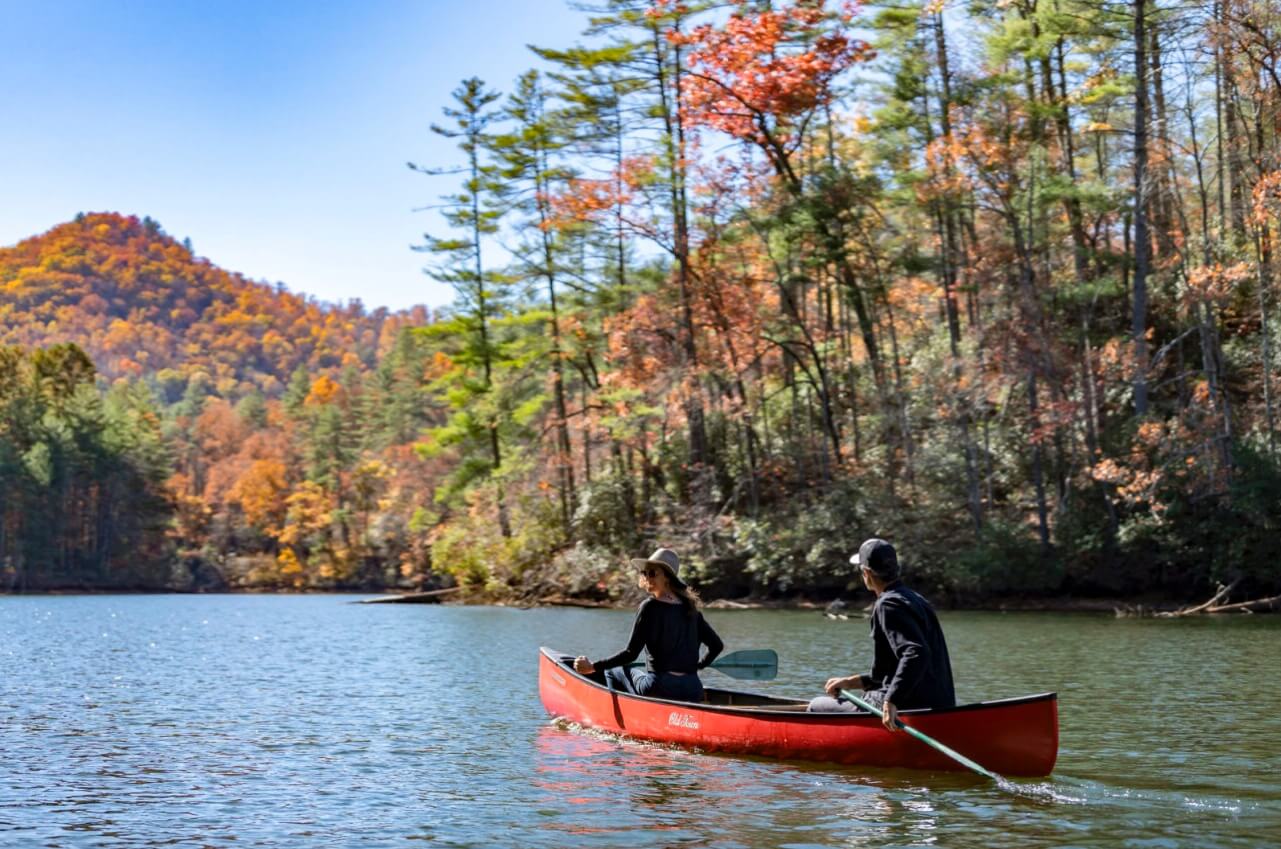 two people canoeing on a lake in the fall