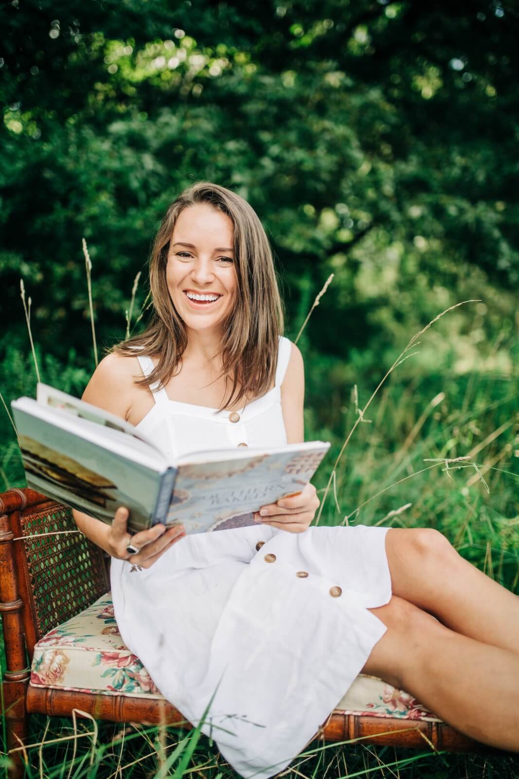 woman outside smiling with open book
