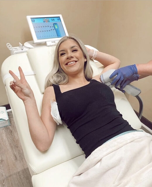 Woman giving peace sign while undergoing miraDry treatment.