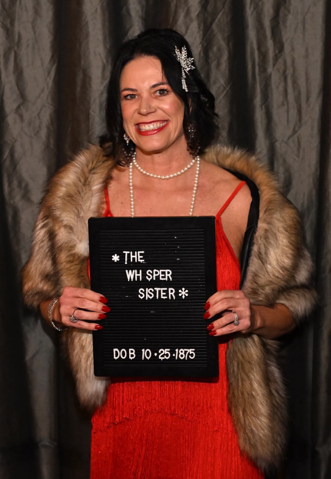 woman dressed in prohibition era attire holding mug shot board