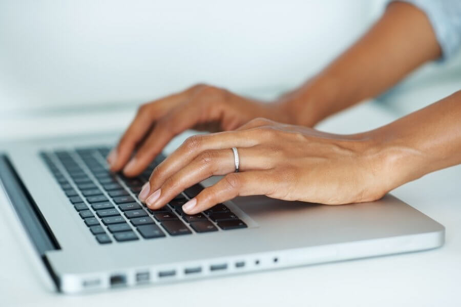A woman's hands typing on a laptop keyboard.