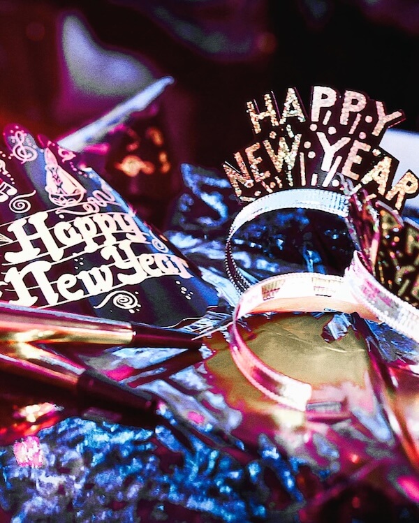 10 Ways to Spend New Year's Eve in Birmingham - 2 Party hats and headbands with "Happy New Year" text sit on a table, surrounded by noisemakers and festive decorations—perfect for your New Year's Eve Birmingham celebration.