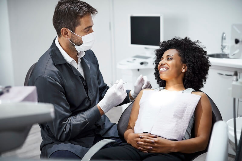 Dentist from The Top Dentists in Nashville conversing with a smiling patient in a dental clinic.