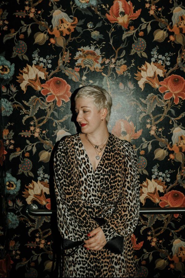 Hunter Claire Rogers poses in front of a floral wall paper