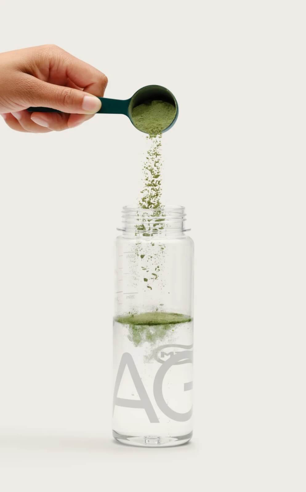 Hand pouring green powder into clear water bottle