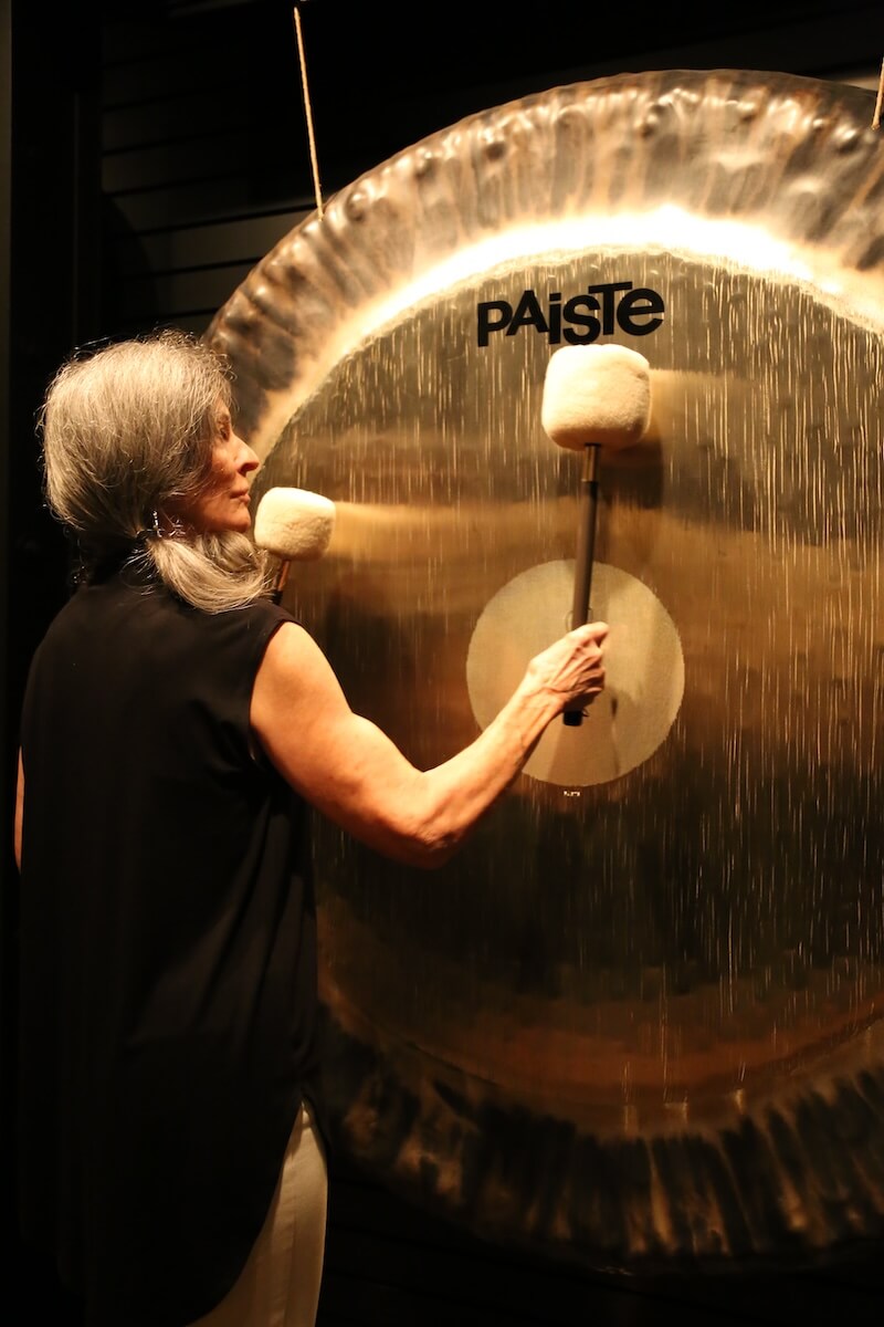 woman with gray hair ringing a gong